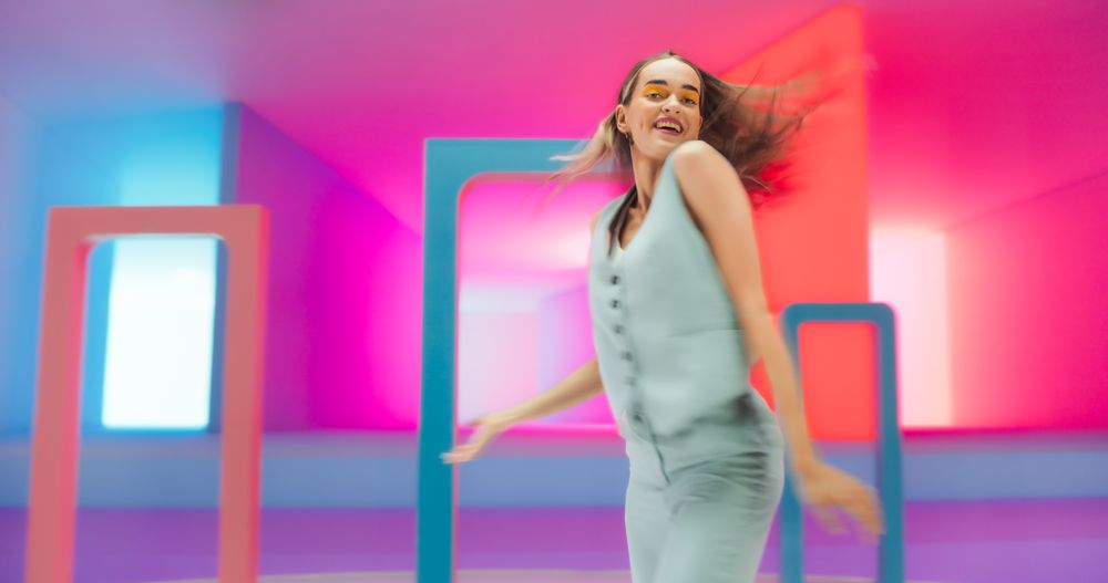 Portrait of a Talented Young Female Artist Showcasing Graceful Movements and Expressive Joyful Emotions with Her Innovative Modern Dance Routine in Colorful Neon Lit Spacious Studio