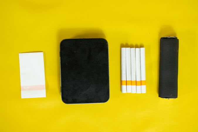 Top view of yellow table with cigarettes and papers