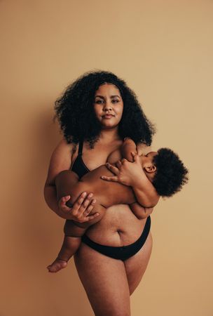 Confident woman holding her baby in her arms as the baby breastfeeds