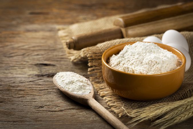 Bowl with wheat flour on the table.