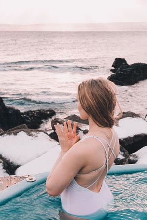 Woman sitting in pool near stones