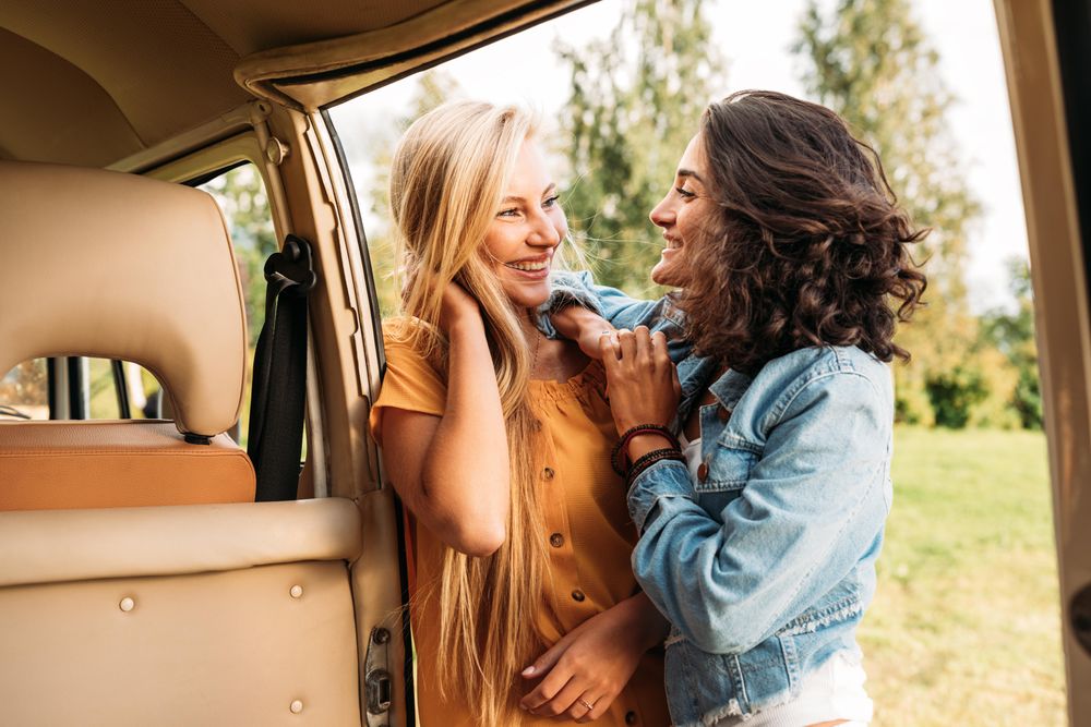 Two friends leaning on an open door to a van