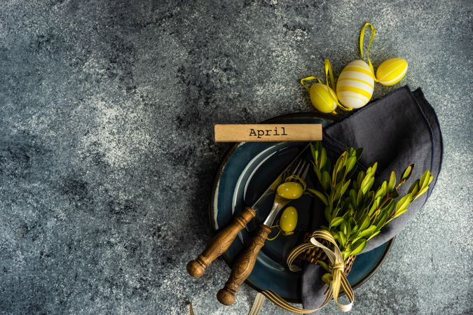 Table setting with branch and yellow mini eggs on grey counter with copy space