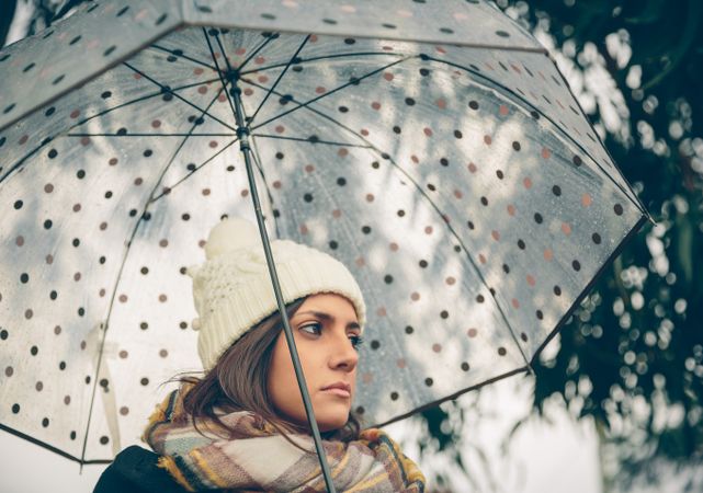 Moody woman walking with umbrella on rainy day