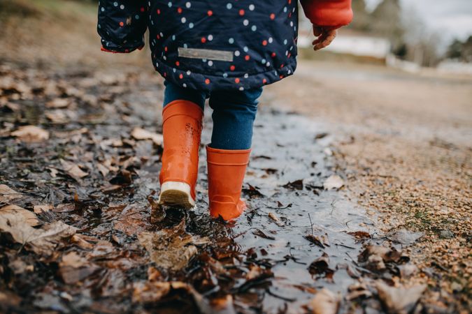 A young girl walking through mud in rubber boots