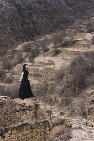 Woman in long blue dress standing in Hamsutl landscape in Dagestan