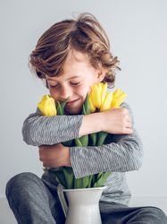 Content boy hugging bouquet of tulips