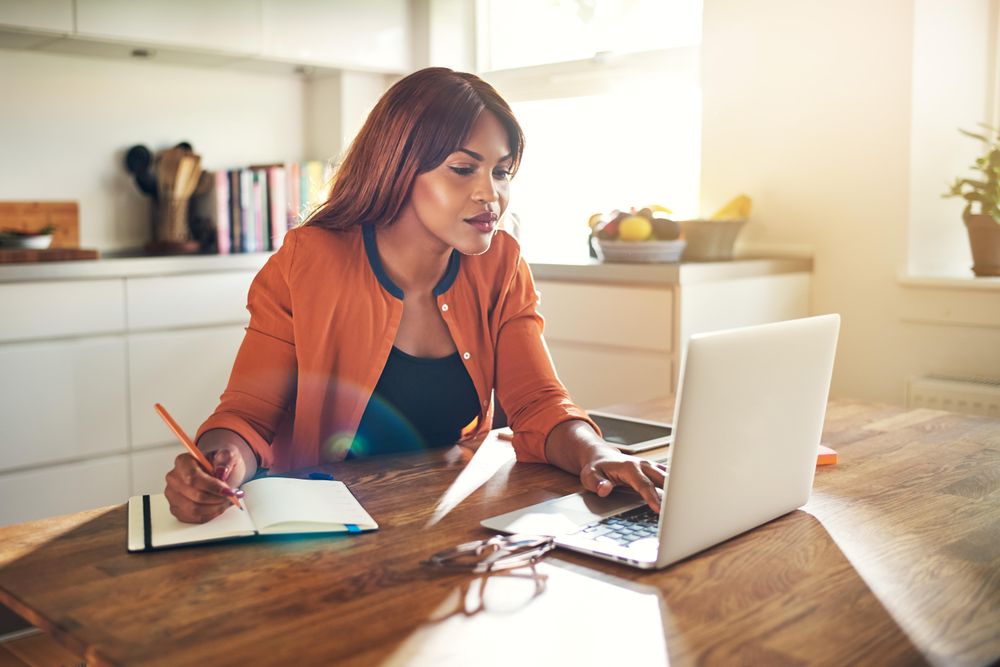 Businesswoman working at her laptop in her kitchen