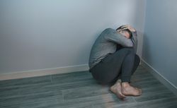 Unrecognizable man with problems sitting in the corner of room