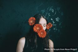 Studio portrait of woman with gerbera flowers on her face 5rAZ10