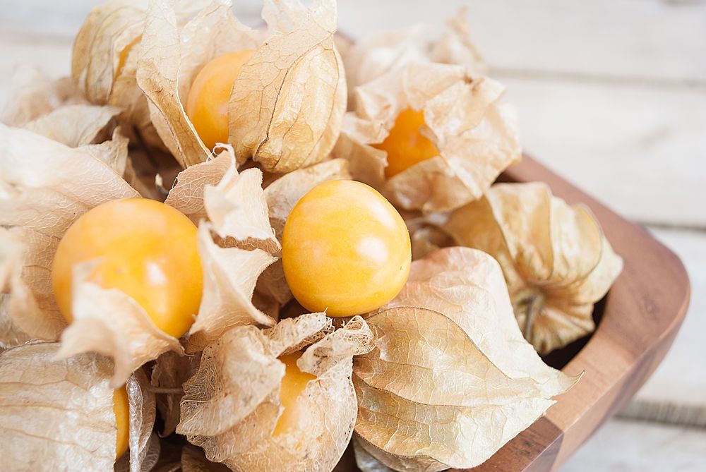 Cape gooseberry (Physalis) in wooden bowl on wooden table, healthy fruit and vegetable