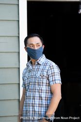 Portrait of man standing outside in front of garage in PPS mask smiling and looking to the side 4Ze2y5