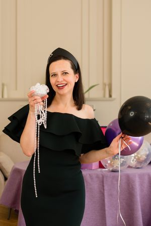 Woman holding jewelry and balloons, birthday party.