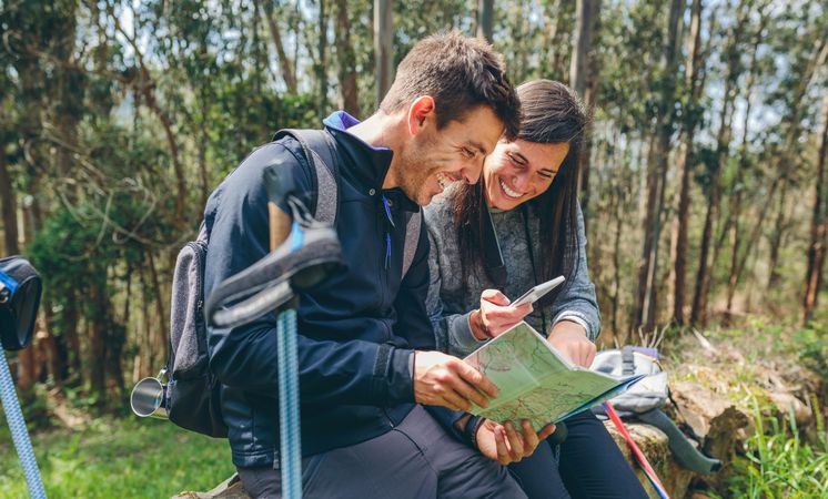 Couple doing trekking sitting looking mobile and map