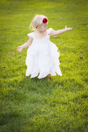 Adorable Little Girl Wearing White Dress In A Grass Field