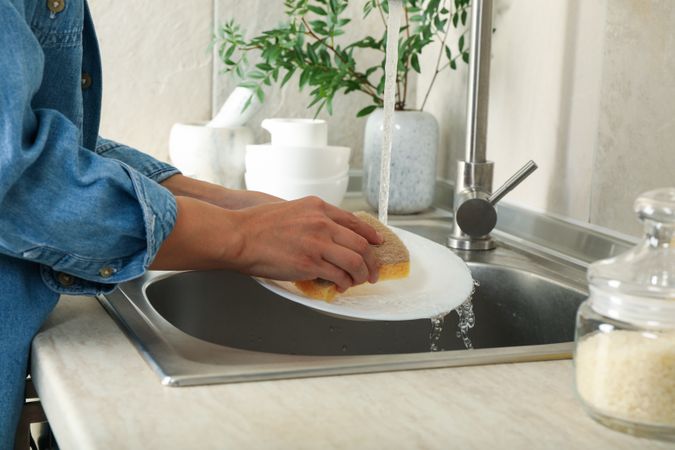 Woman washing a plate in the kitchen sink