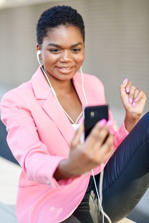 Smiling female wearing suit with pink jacket talking on video call