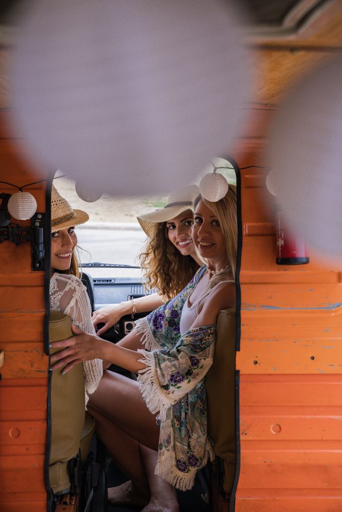 Smiling girlfriends on front seat of car looking at camera