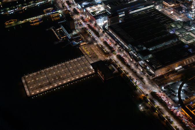 Aerial View of Docks in New York City. Helicopter Shot of a Highway Next to the Port in New York City. Panoramic View with Traffic Around a Big City with Industrial Hub in the Background