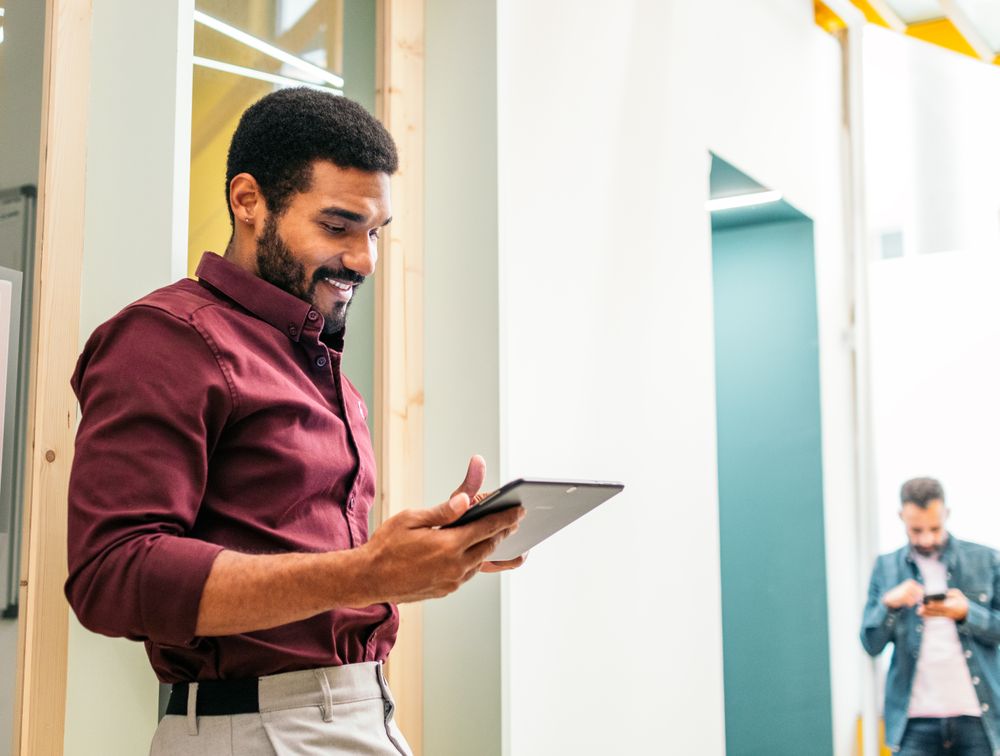 Smiling man in shirt working with a tablet in a coworking