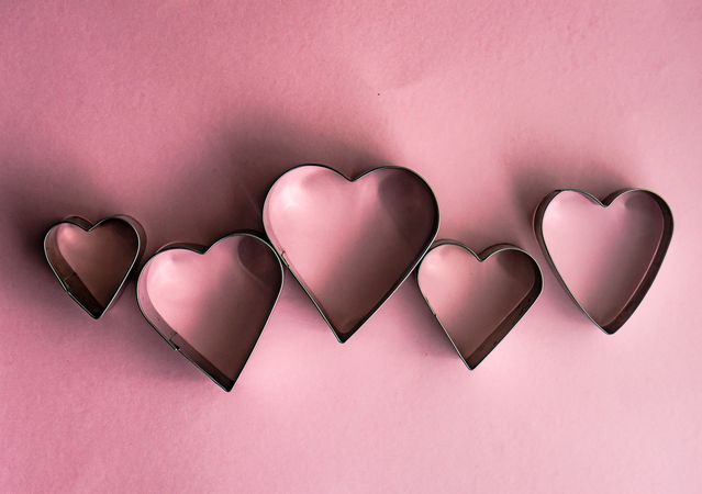 Heart shaped cookie cutters on pink background