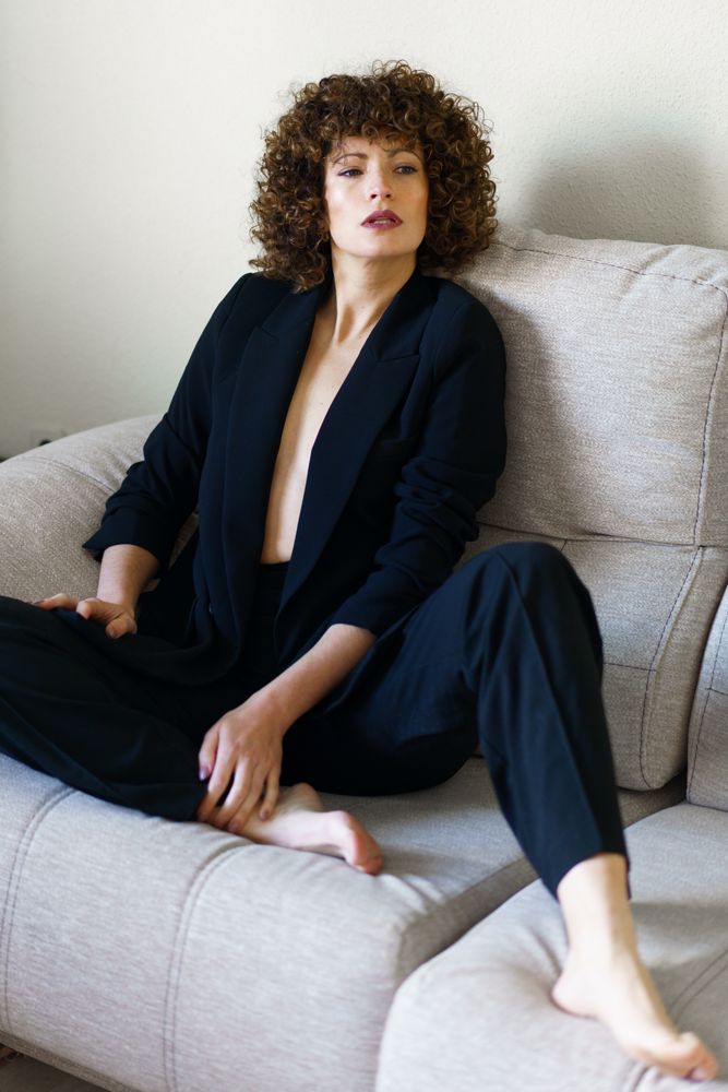 Woman in dark suit relaxing on sofa at home