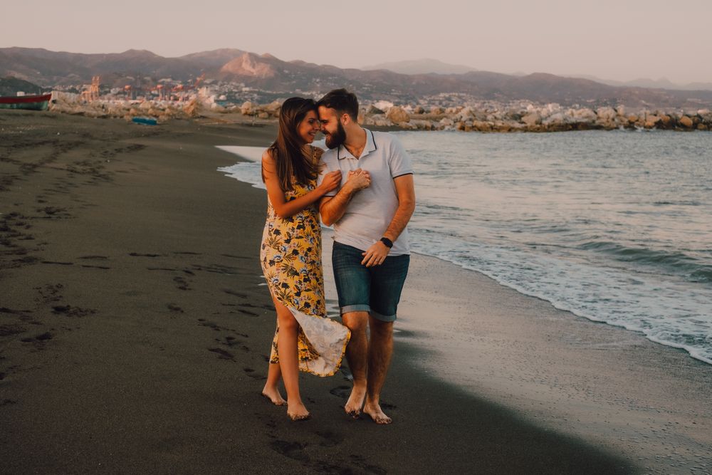 Lovely couple walking holding hands on sandy beach