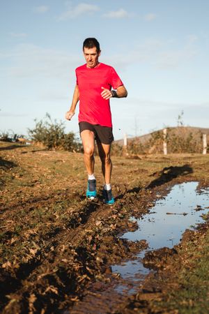 Sportsman running on dirty road in countryside