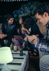 Happy man reading his smartphone at a party with friends