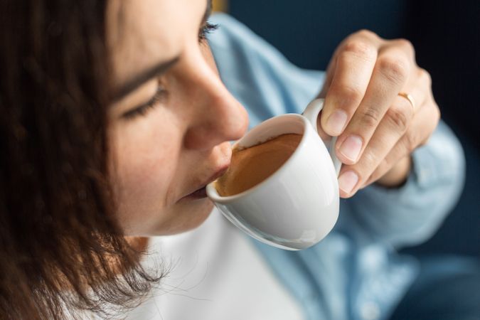 Woman drinking coffee from small cup at home