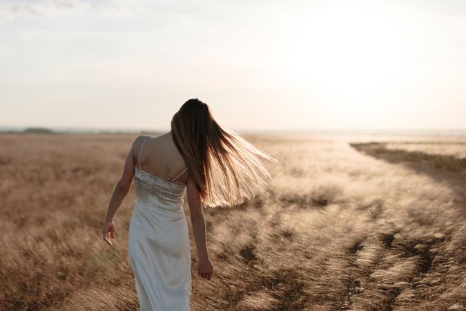 Back view of young woman walking in an open field