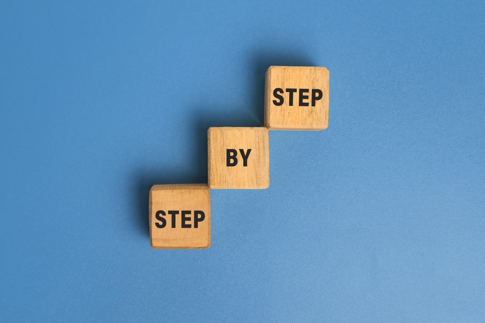 step by step word on wooden blocks staircase isolated on blue background. concept of success progress or career