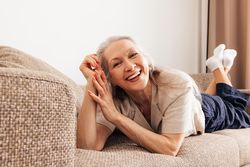 Grey haired woman lying on her stomach on sofa