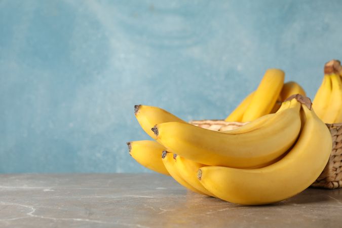 Basket and bananas against blue background. Fresh fruit