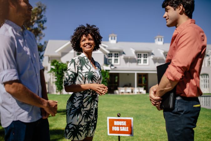 Young couple with real estate agent visiting house for sale