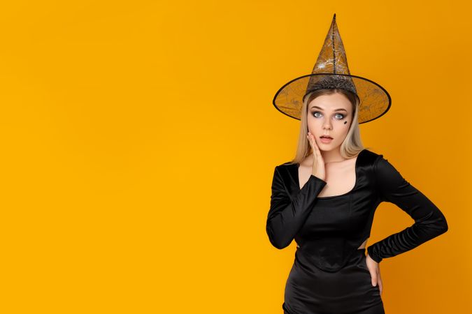 Concept of Halloween, young woman on yellow background