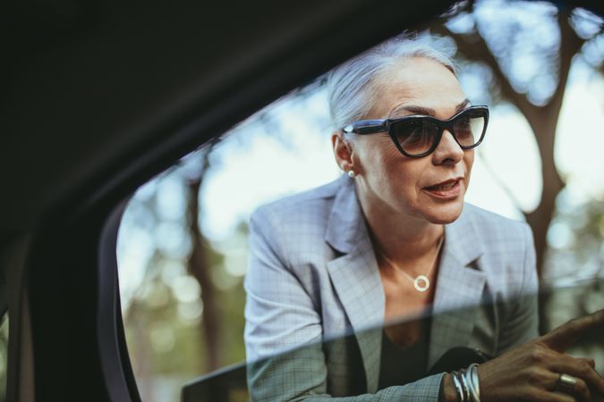 Businesswoman in sunglasses talking with cab driver