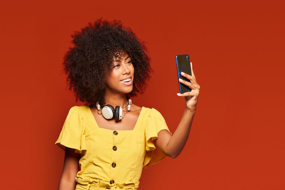 Trendy Black woman taking selfie with smartphone