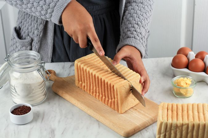 Person slicing loaf of bread in half