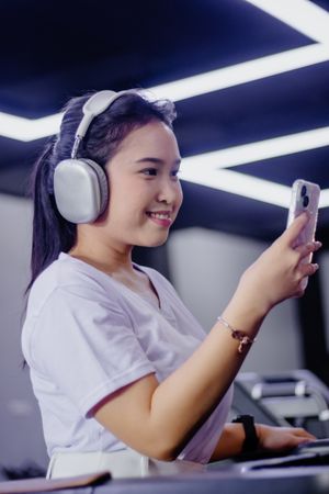 Engaging Asian woman exercising, listening music, using a smartphone