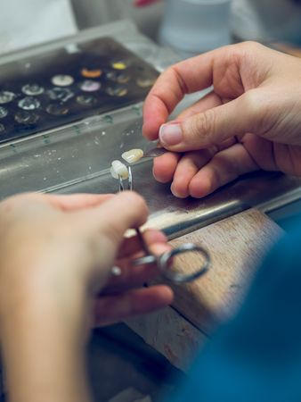 Anonymous dental technician working with artificial teeth