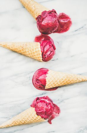 Four cones of dark berry ice cream on marble slab