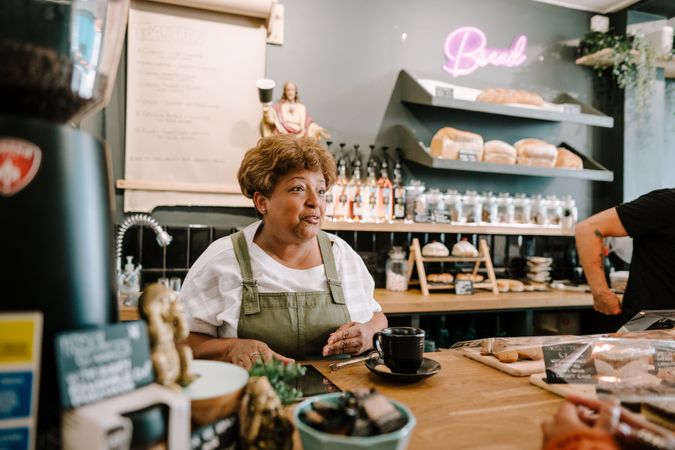 Older Black woman serving coffee in cafe