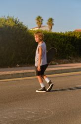 Calm skater walking with skateboard in sunset