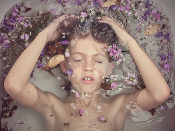 Boy underwater in bathtub with flowers