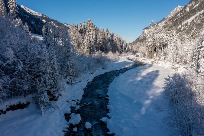 River in winter deep snow scenery, drone aerial view in the Bavarian Alps, Germany