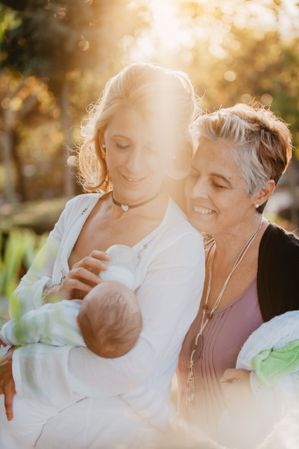 Two mature women feeding a baby with a bottle