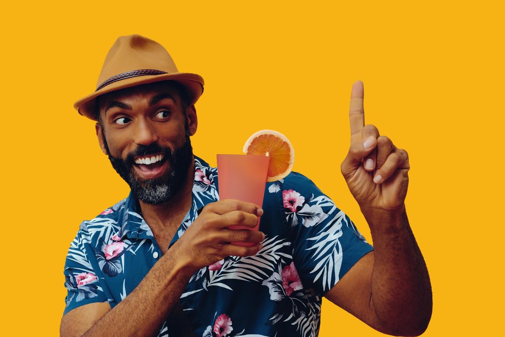 Excited male giving pointing up while wearing colorful shirt with yellow background