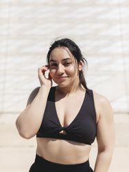 Natural portrait of a young woman with straight dark hair, happy, looking at the camera, after a sports and exercise session outdoors