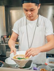 Young male decorating prepared Japanese dish